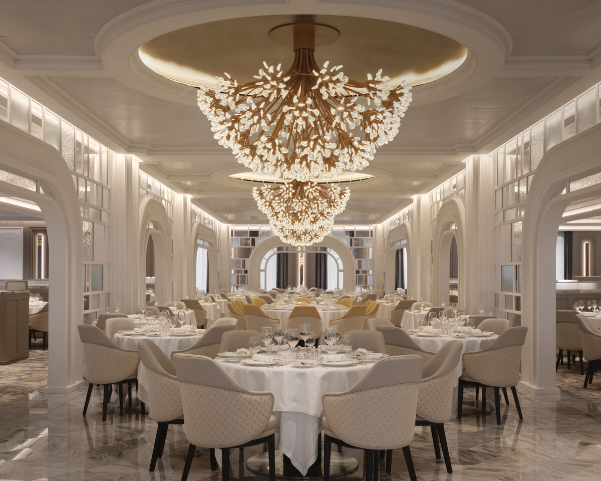 The elegant Grand Dining Room aboard an Oceania Cruises ship, with a crystal chandelier, arched alcoves and tables set with white linens