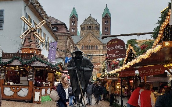 The pilgrim statue rises above Christmas Market stalls selling gluehwein along Speyer's Maximilianstrasse